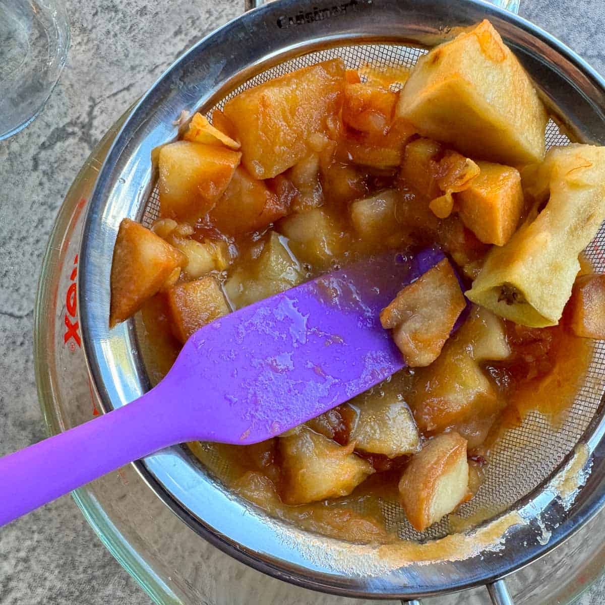 straining vinegar from apples into a large measuring cup.