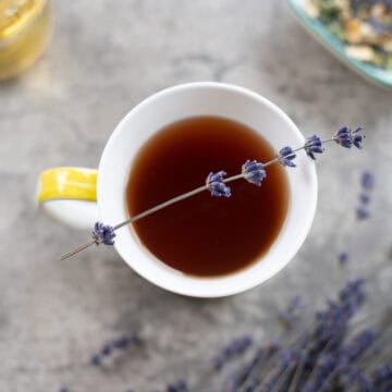 lavender tea in a cup with lavender around it.