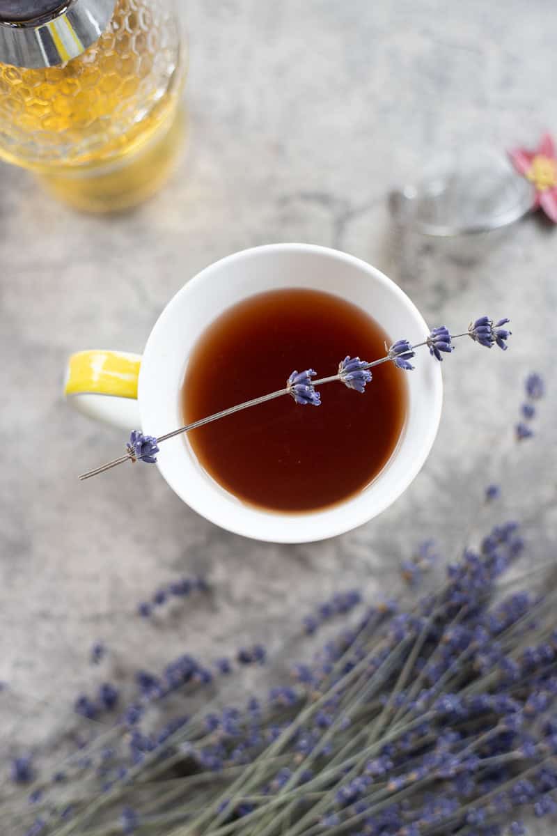 lavender tea in a cup with lavender around it.