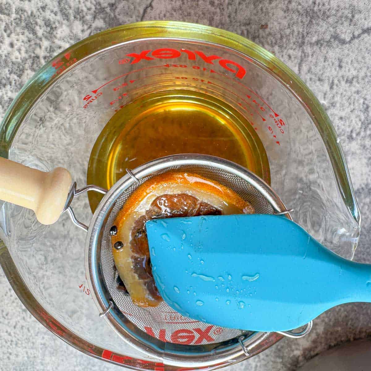 straining syrup into measuring cup through a small strainer. 