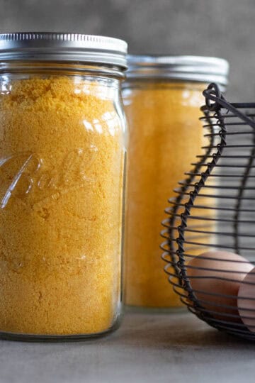 2 jars with freeze dried eggs with a basket of eggs next to it.