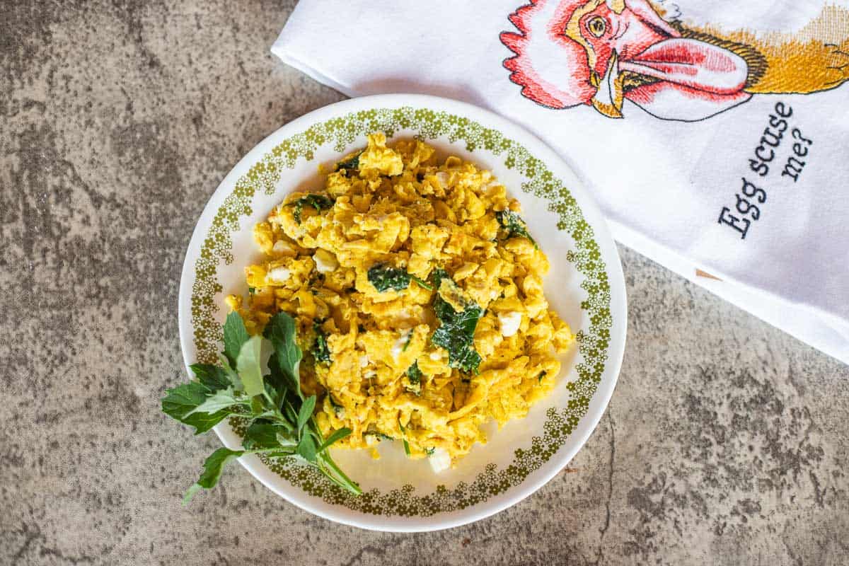 a plate of scrambled eggs with lamb's quarters and feta.