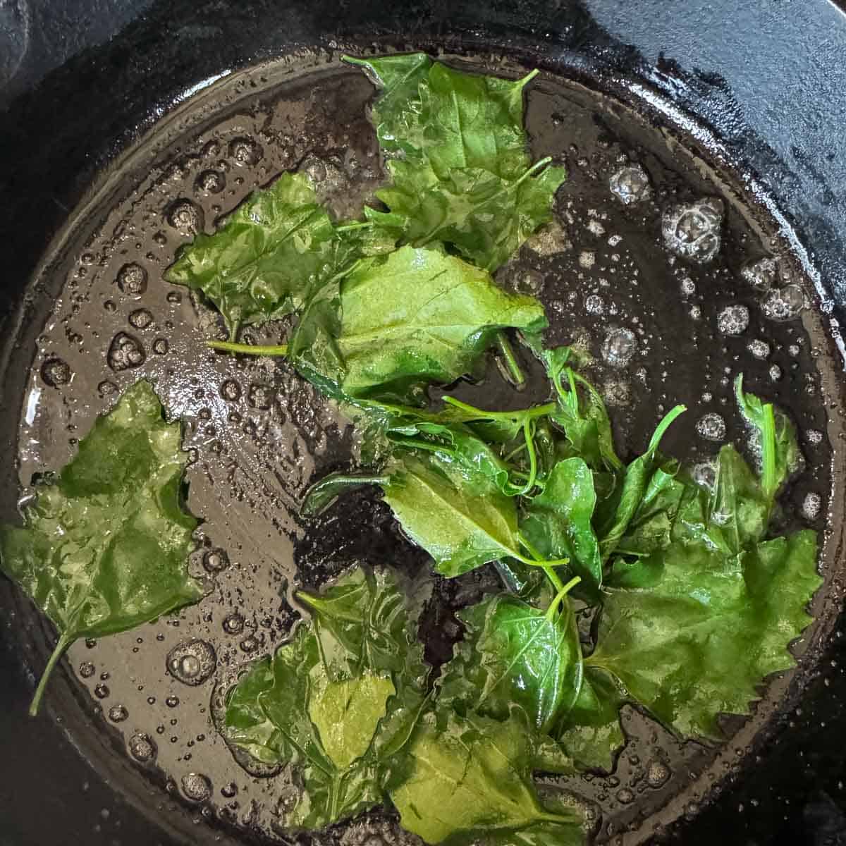 lambs quarters being sauted in butter. 