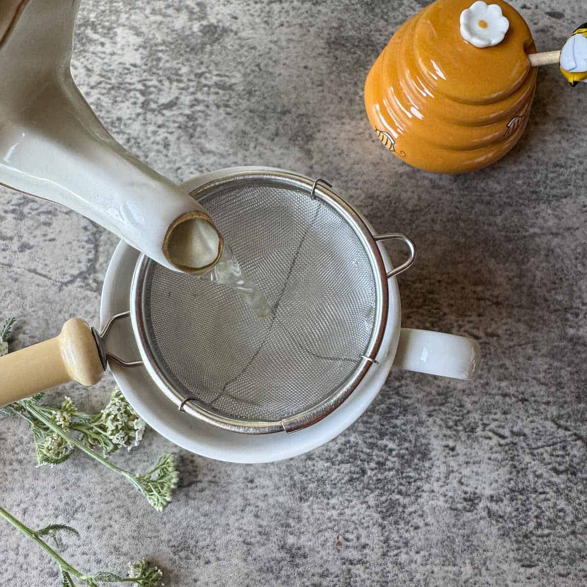 pouring tea through a strainer into a cup. 