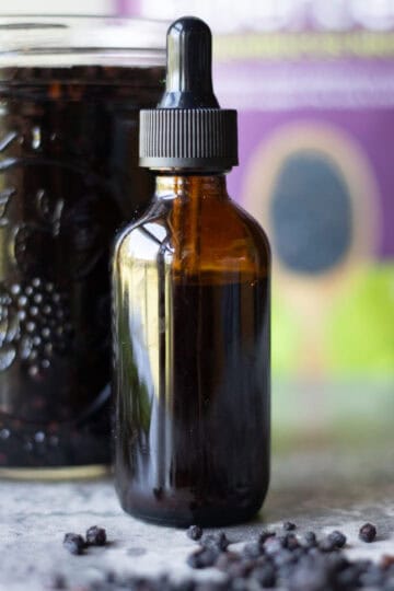 elderberry tincture in a bottle with elderberries around it.