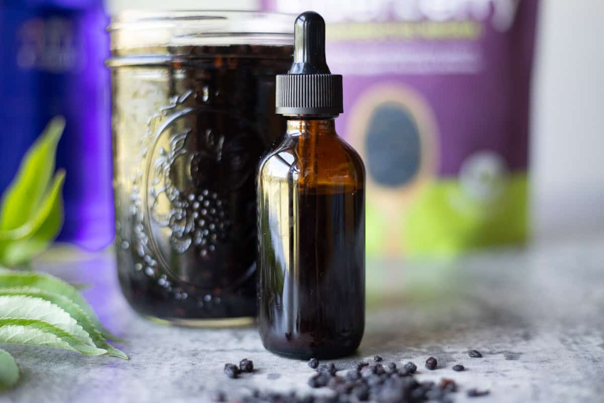 elderberry tincture in a dropper bottle with more in a mason jar and a bag. 