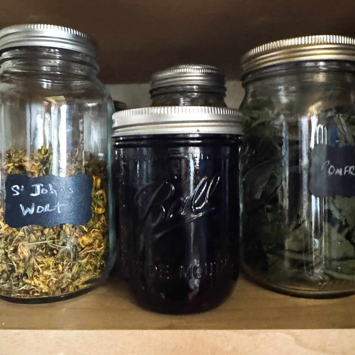 a jar of elderberries soaking in alcohol with other jars next to it. 
