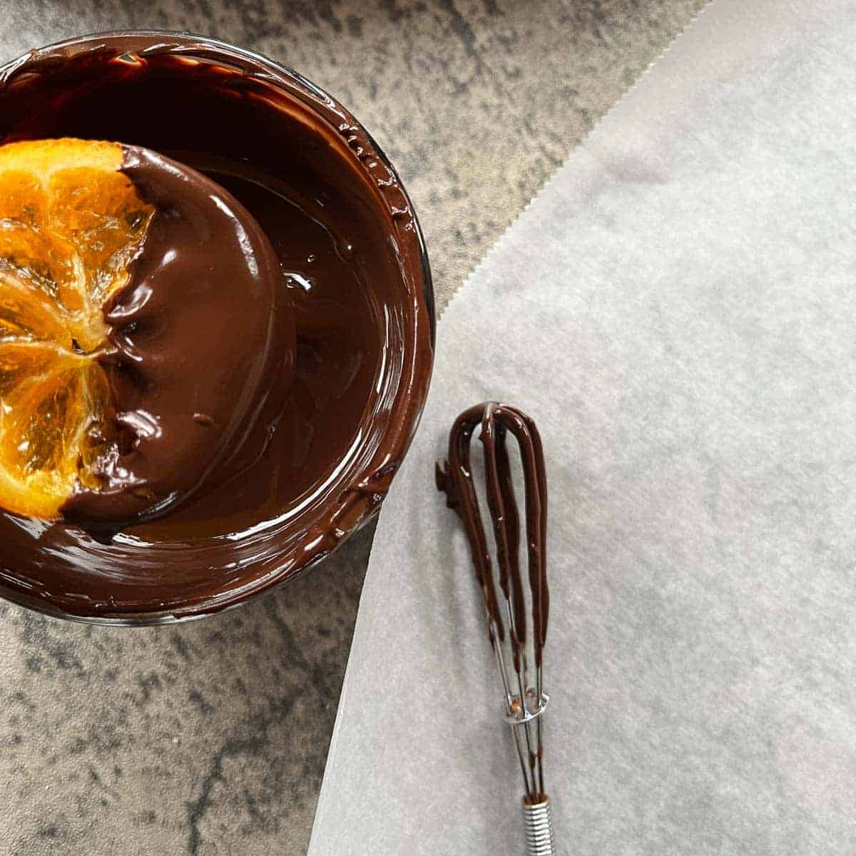 candied orange slices being dipped in dark chocolate.