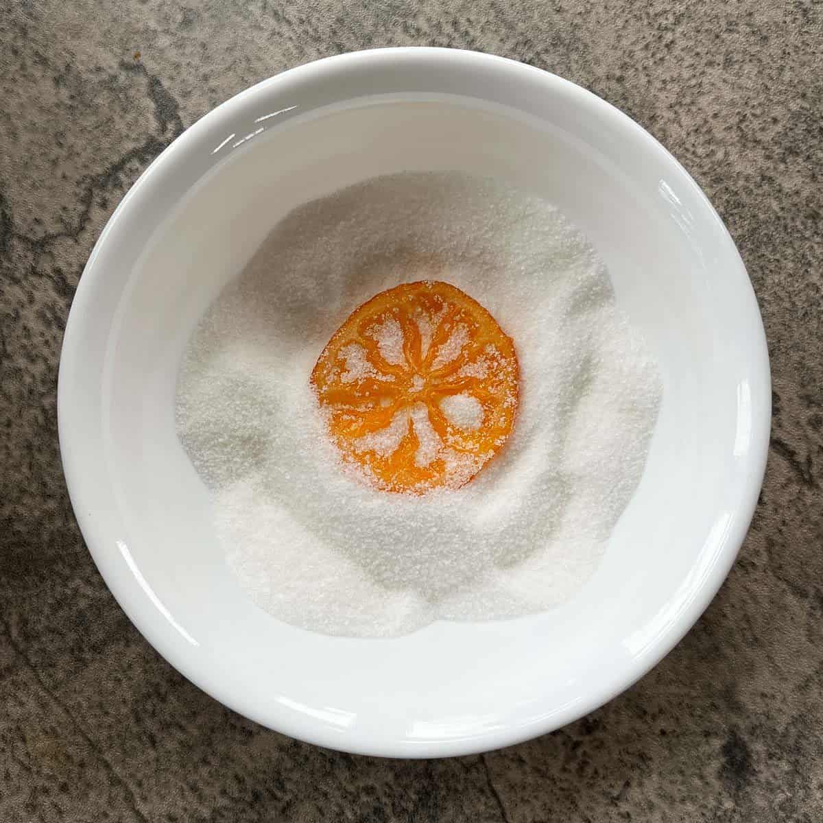 candied orange slices in a bowl of sugar.