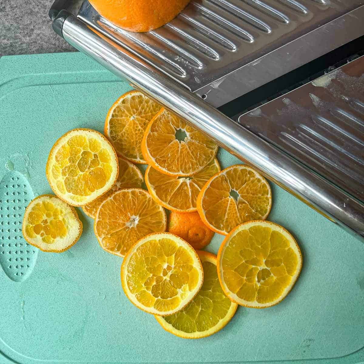 oranges slices with mandoline on a aqua cutting board.