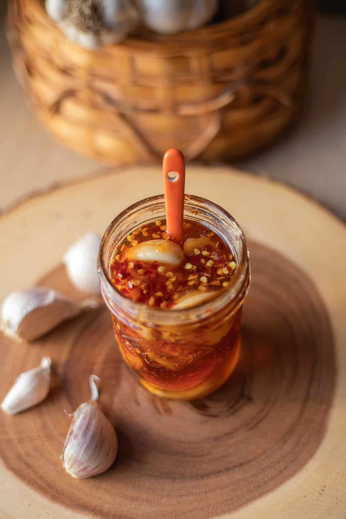 garlic fermented honey with a spoon in it and garlic cloves around it.