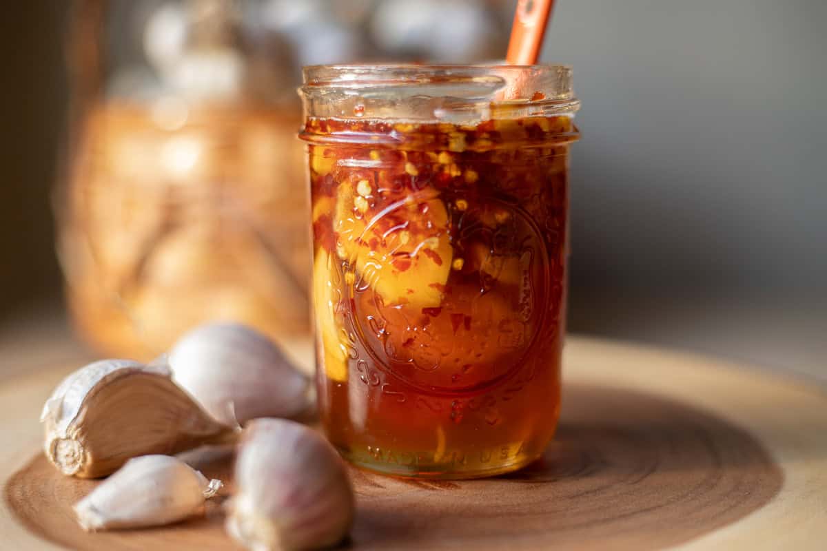 fermented garlic honey in a jar with garlic around it and behind it.