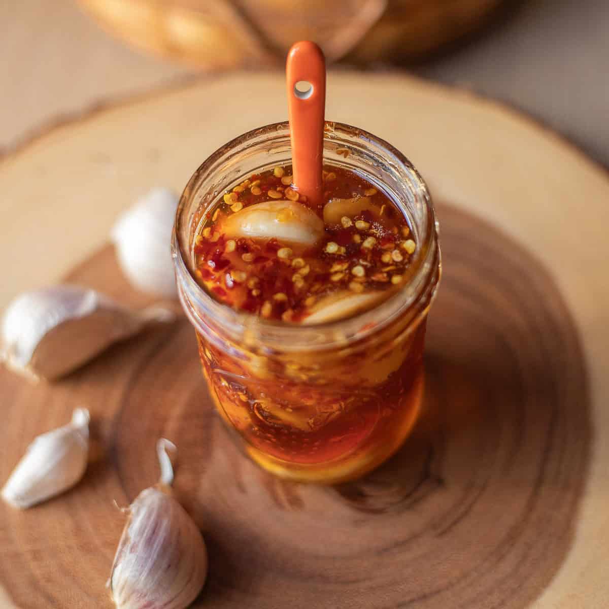 a jar of fermented honey garlic with garlic cloves around it .