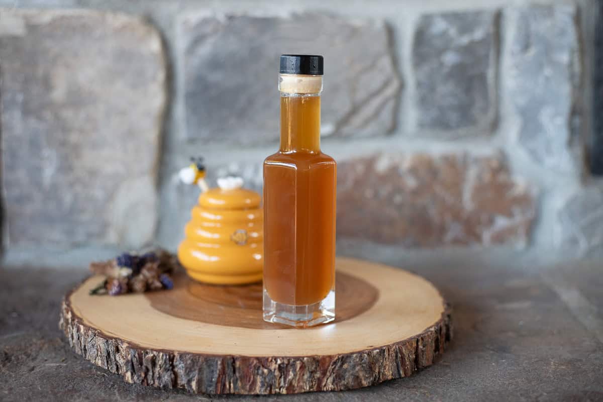 Oxymel bottle with honey behind it. 