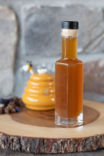 oxymel in a bottle with honey and herbs.