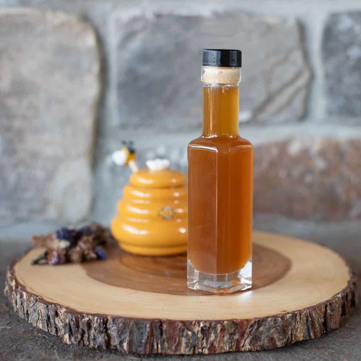 oxymel in a bottle with honey and herbs.