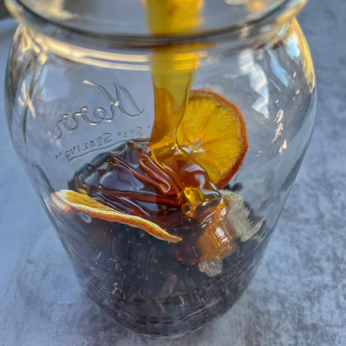 elderberries, citrus slices, and honey in a jar.