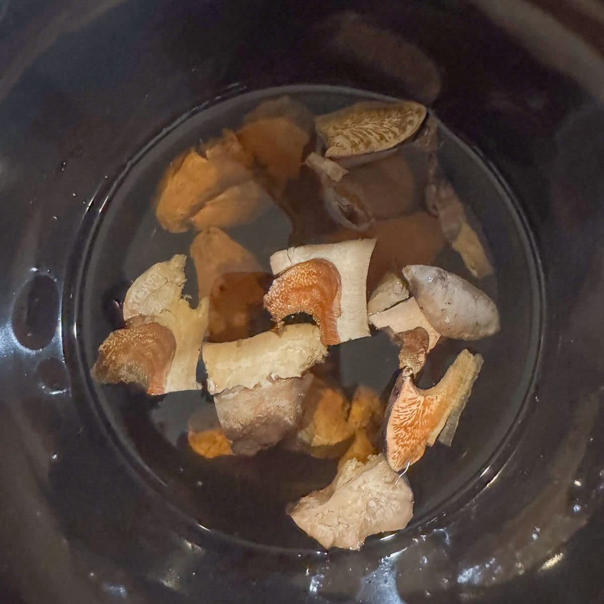 mushroom chunks in water in a slow cooker.