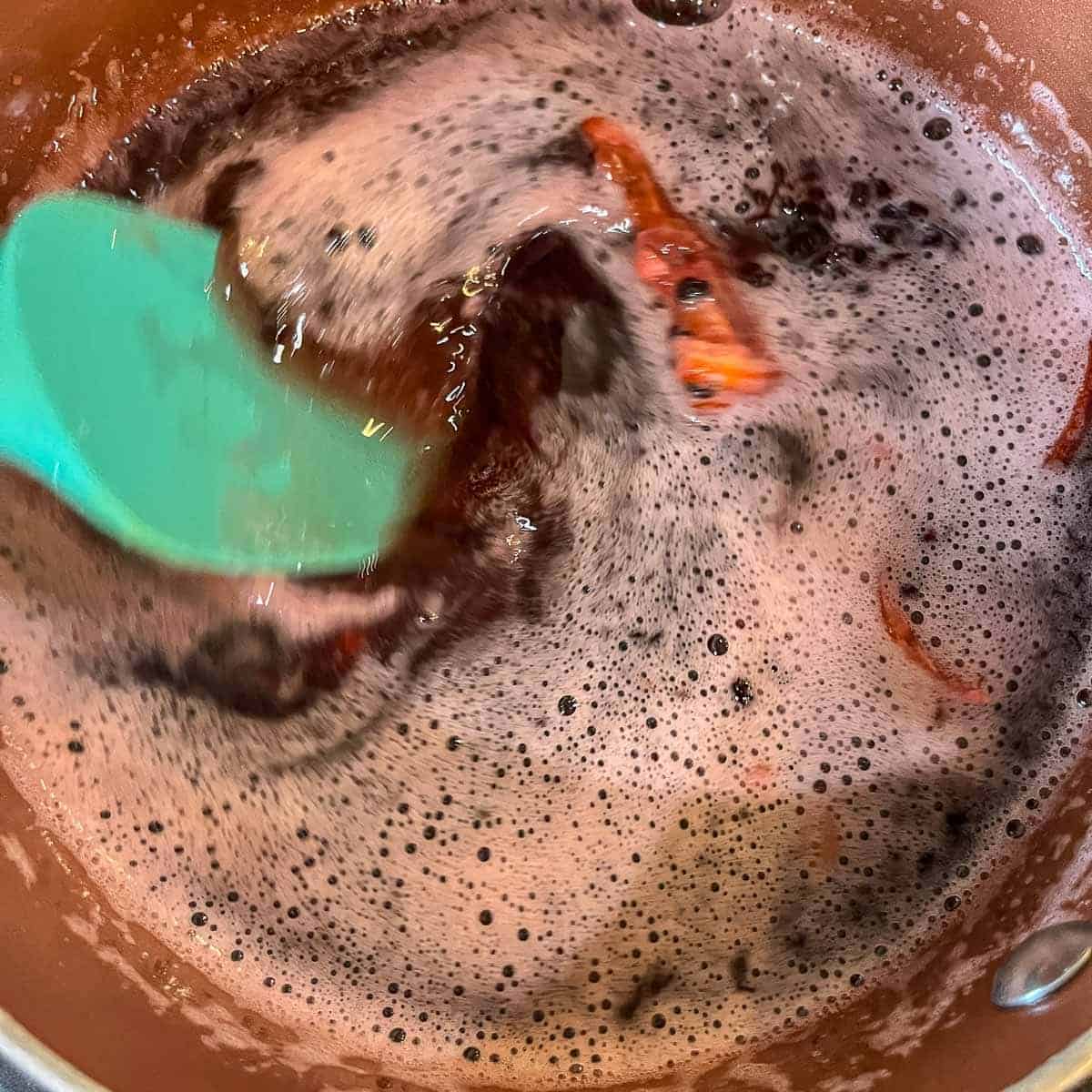 stirring elderberries and honey in a pot.