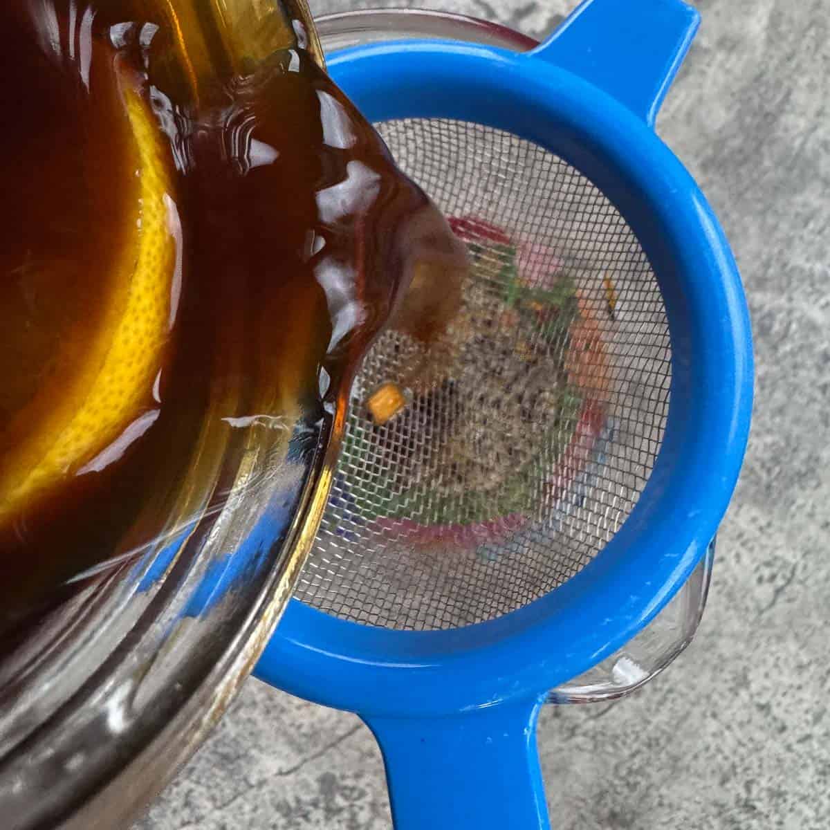 pouring switchel through strainer into a jar.