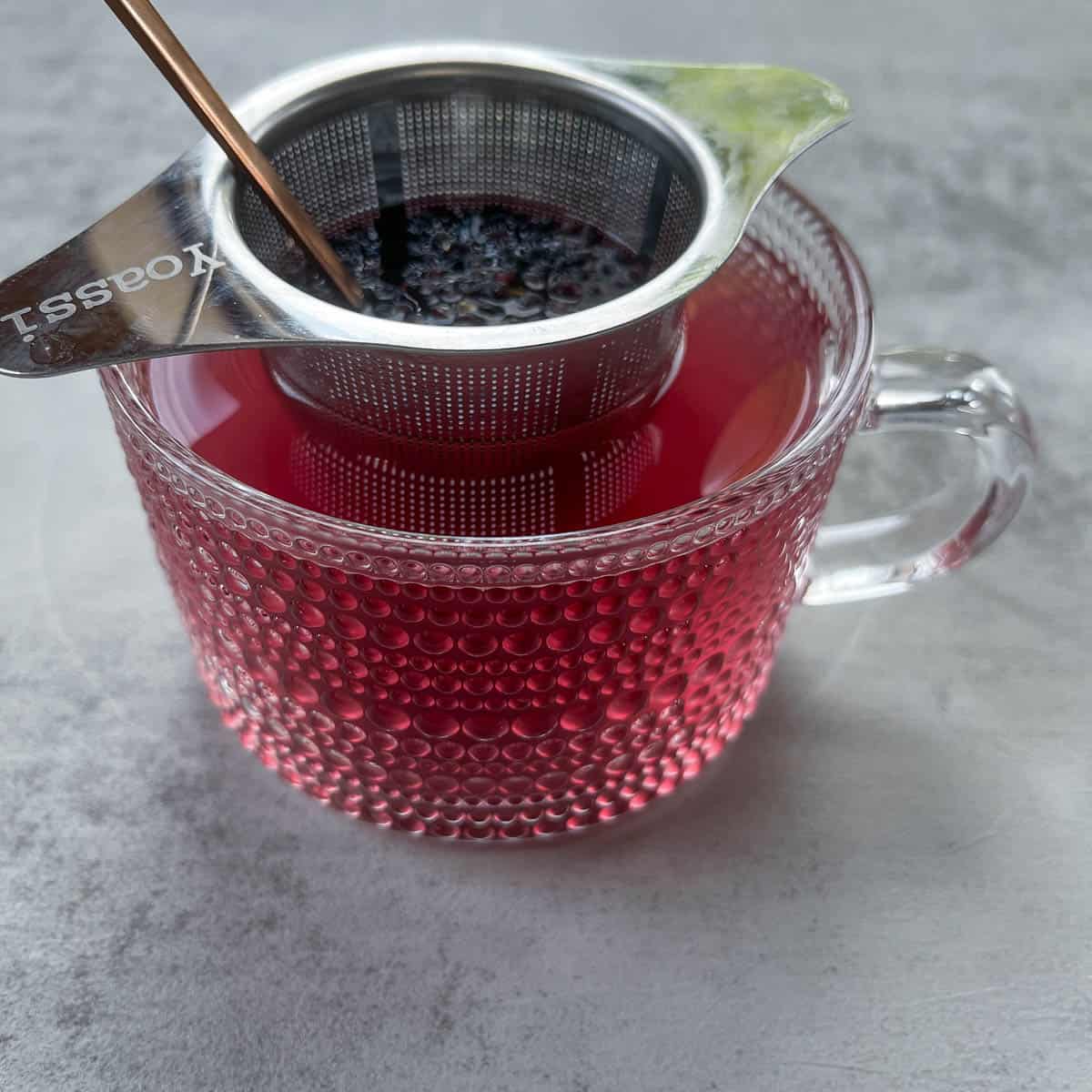 tea strainer in a tea cup with elderberries.