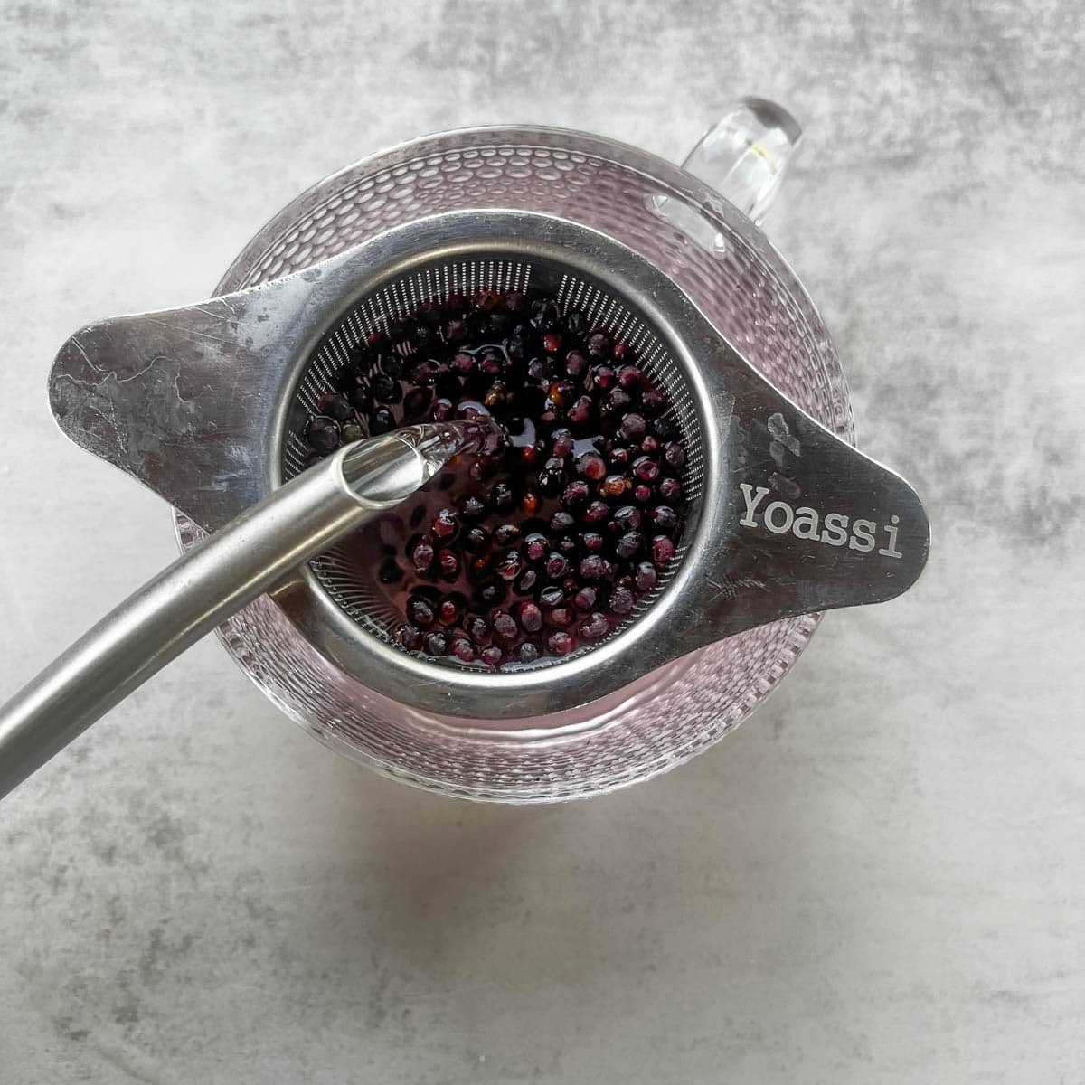 adding water to elderberries in a tea cup.