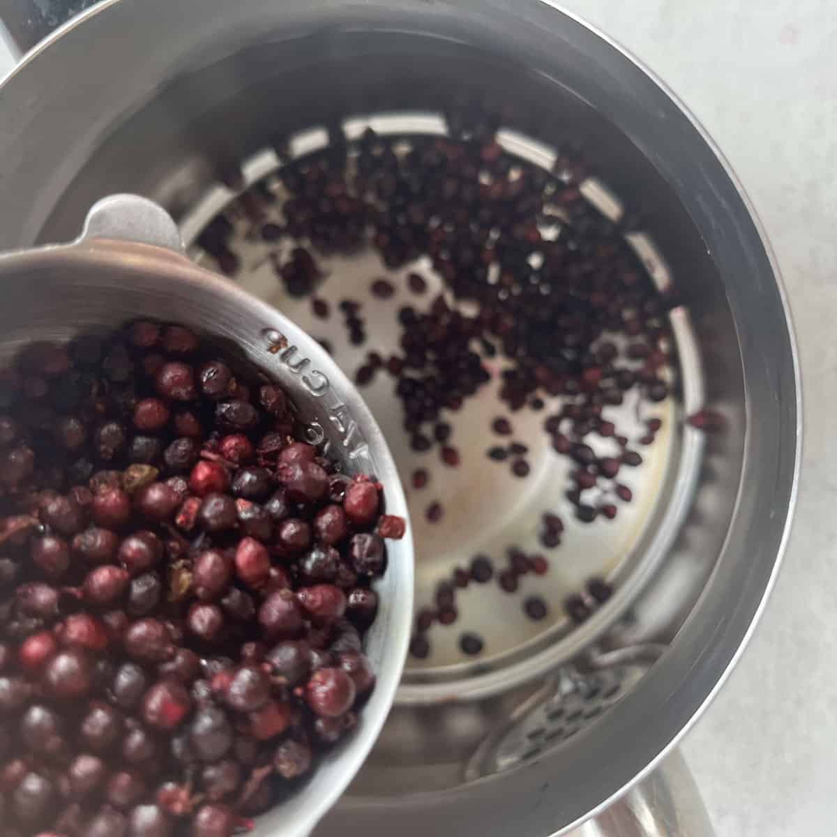 adding elderberries to a tea pot