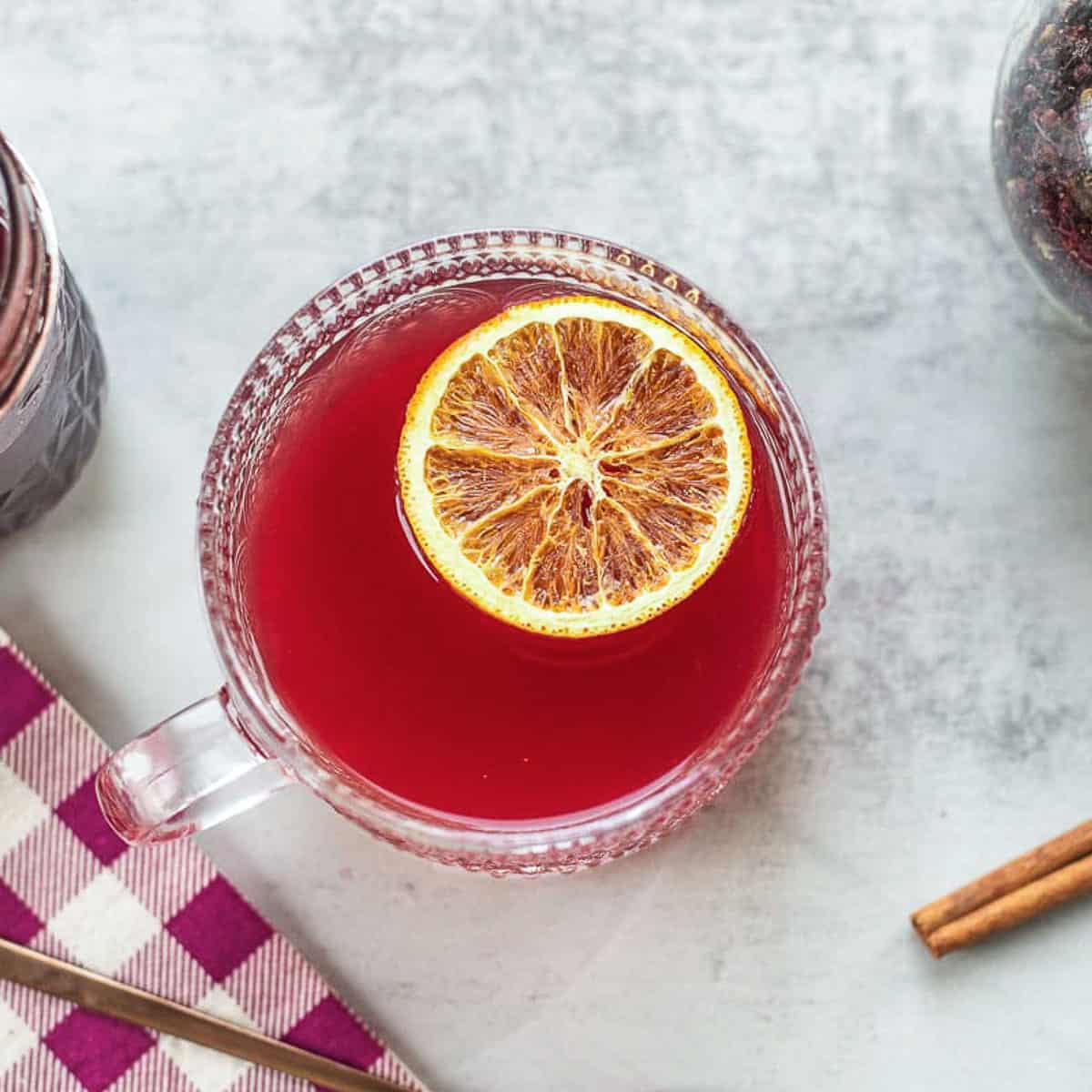 elderberry tea in a cup with orange slice, cinnamon stick, and elderberry syrup.