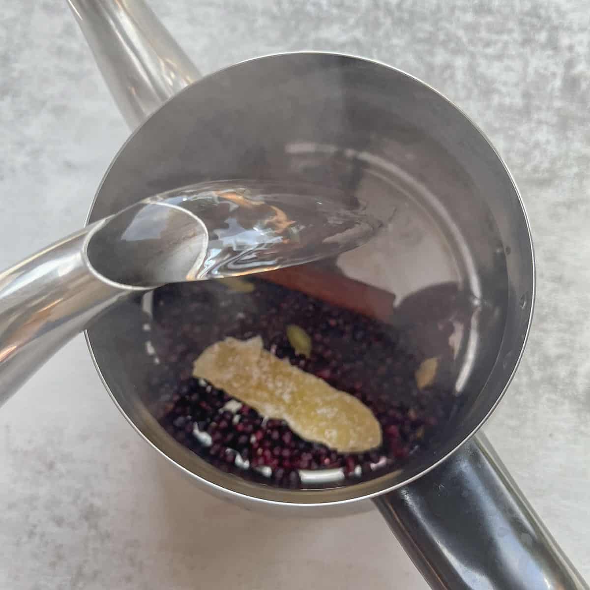 pouring boiling water over elderberries in a tea pot.