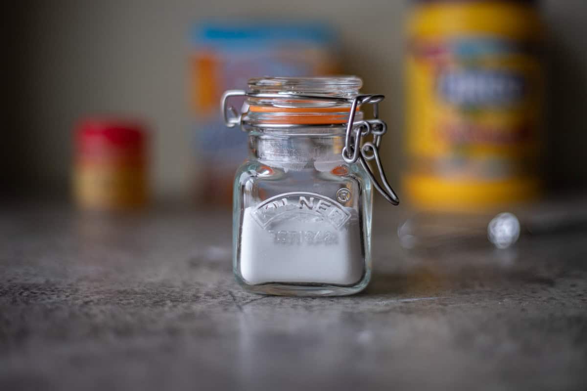 homemade baking powder in a jar with ingredients in the background.