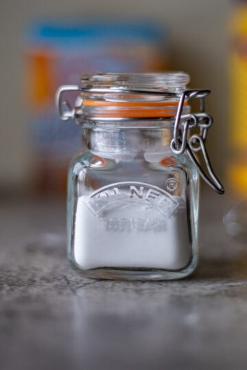 homemade baking powder in a jar with ingredients in the background.