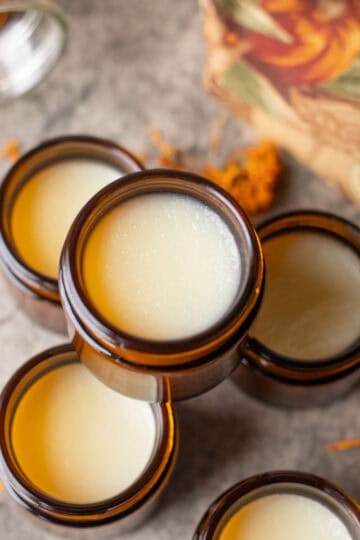 tallow balm in jars with dried calendula flowers scattered around them.