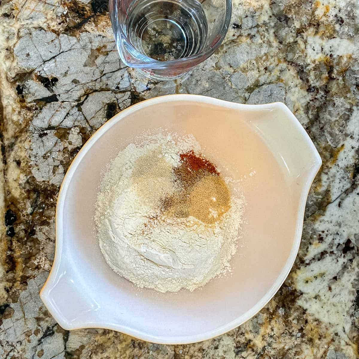 vegan fried chicken seasoning and flour in a white bowl