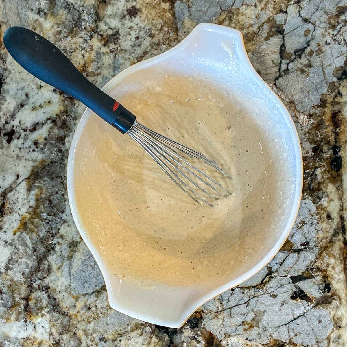 batter in a white bowl with a whisk
