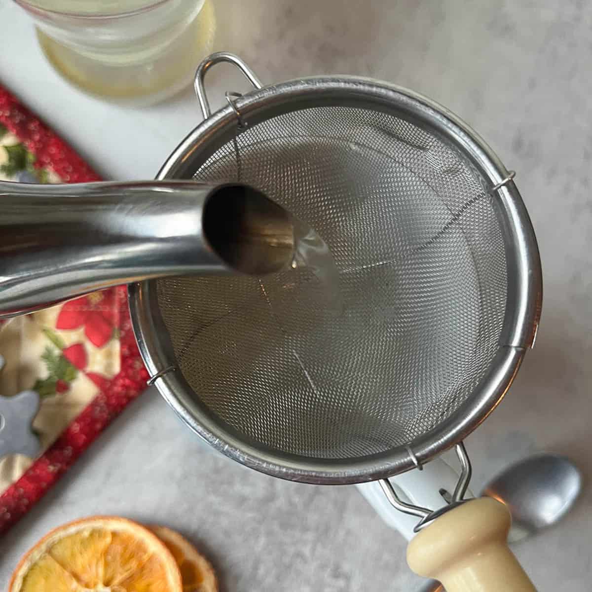 straining pine needle tea into a cup