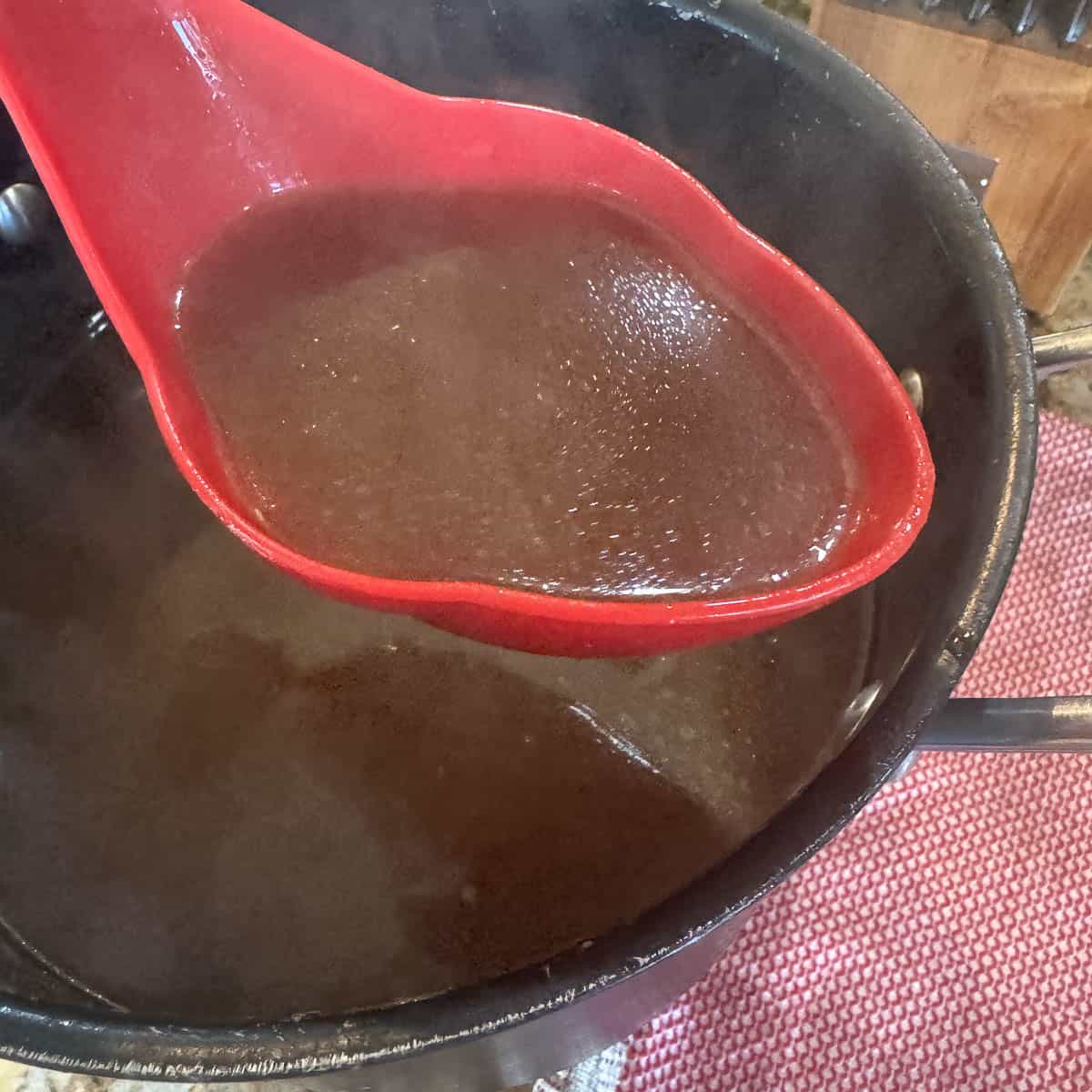 pressure canner bone broth being ladled with a red ladle.
