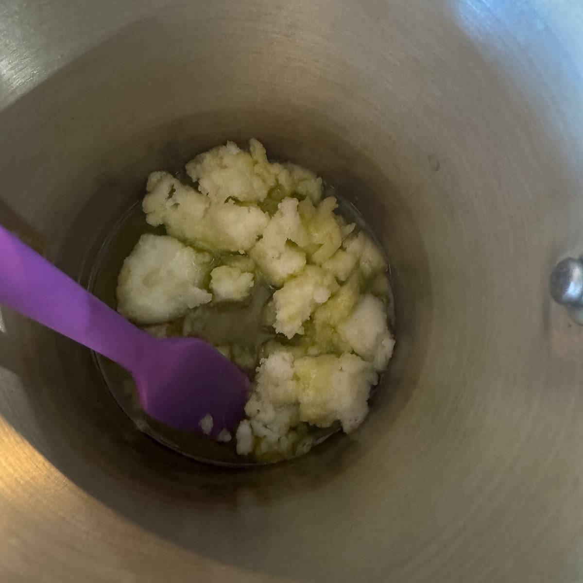 tallow melting in a pot with a purple spatula