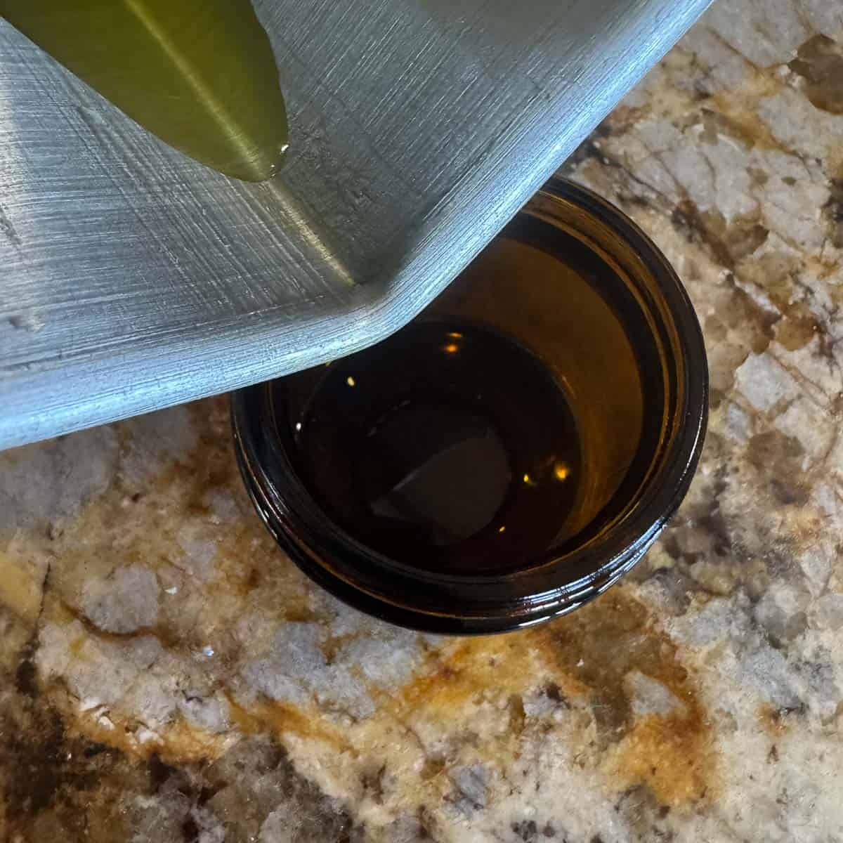 pouring oil into a small amber jar