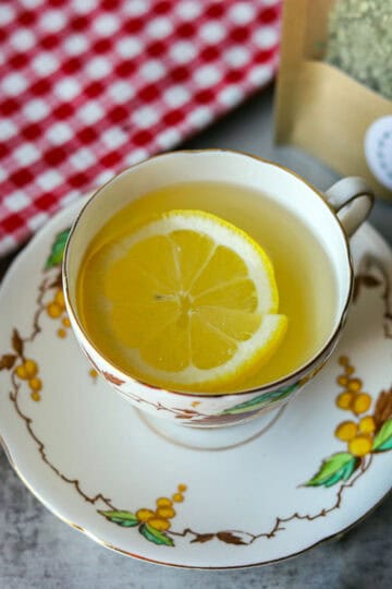 mullein tea in a cup with lemon wedge and checkered napkin behind it.