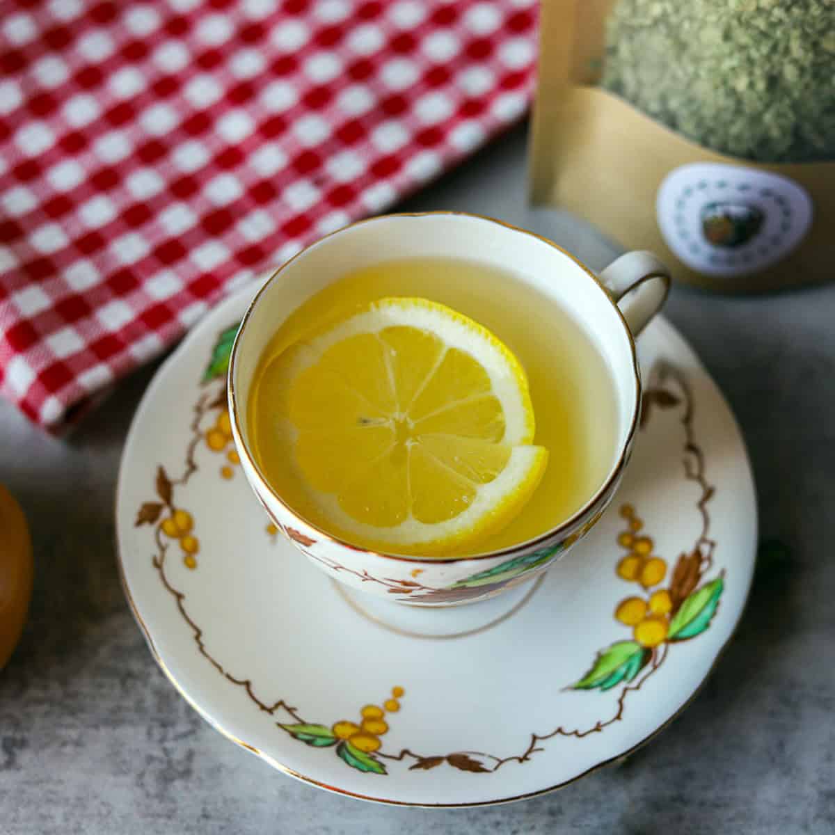 mullein tea in a cup with lemon wedge and checkered napkin behind it.
