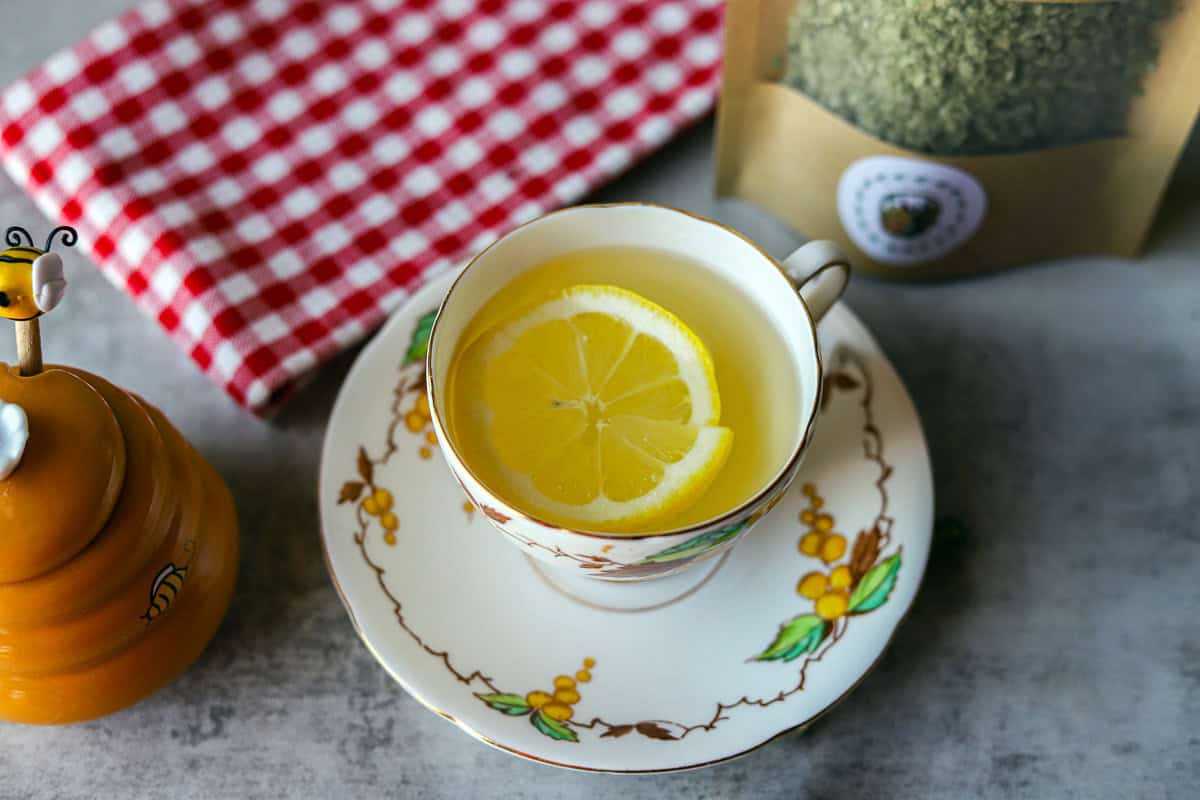 mullein tea with a slice of honey with a red and white checkered napkin, and honey.