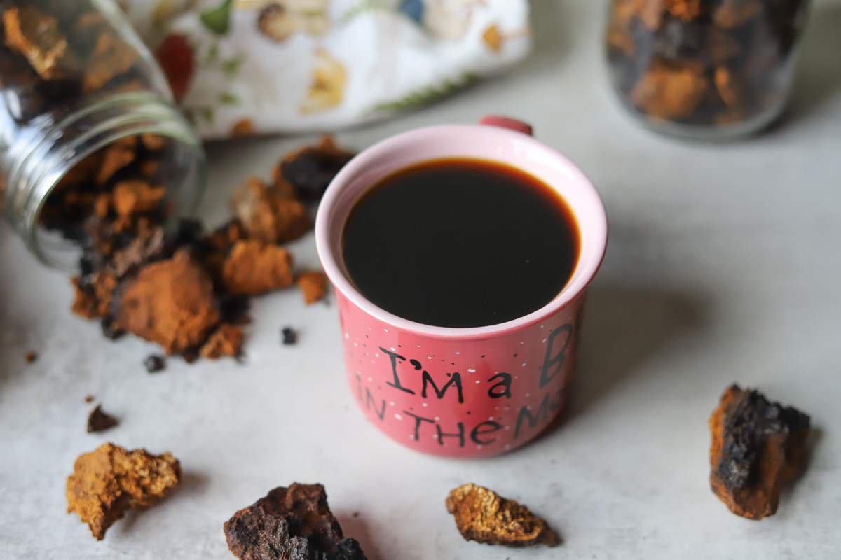 a cup with chaga coffee surrounded by chunks of chaga