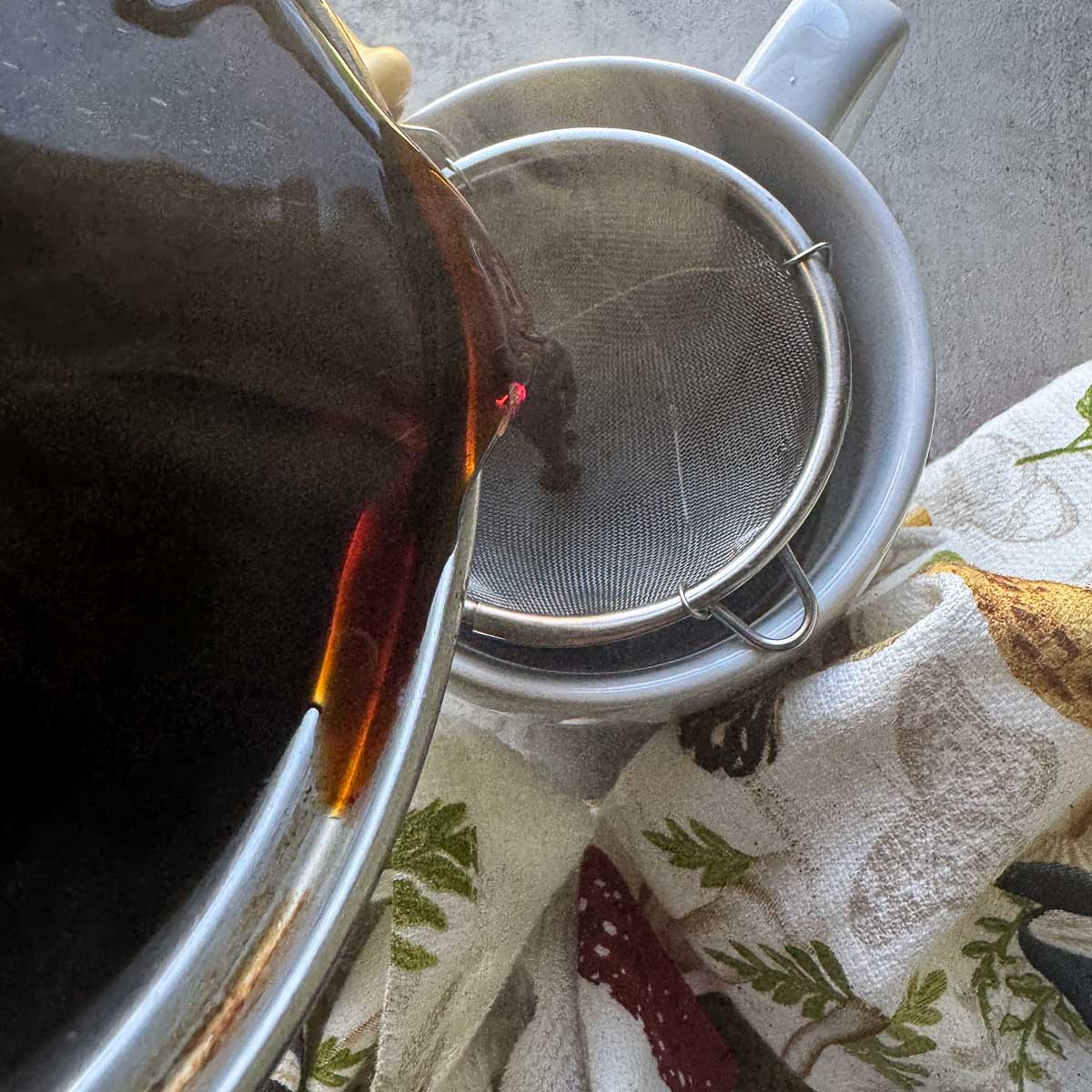 pouring chaga tea through strainer into cup