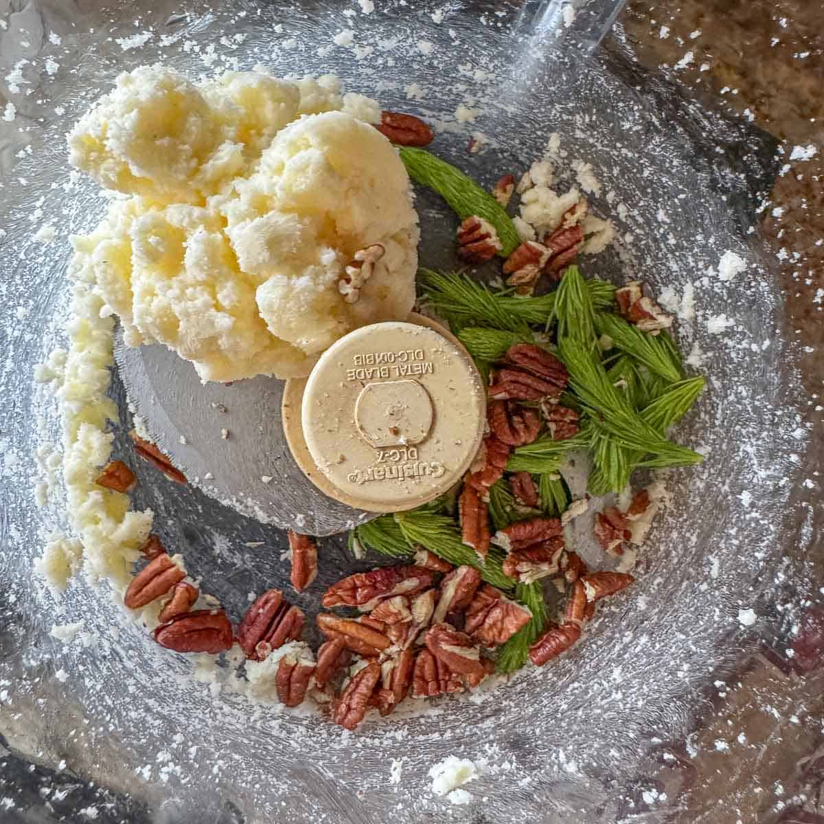 shortbread dough, pecans, and spruce tips in a food processor