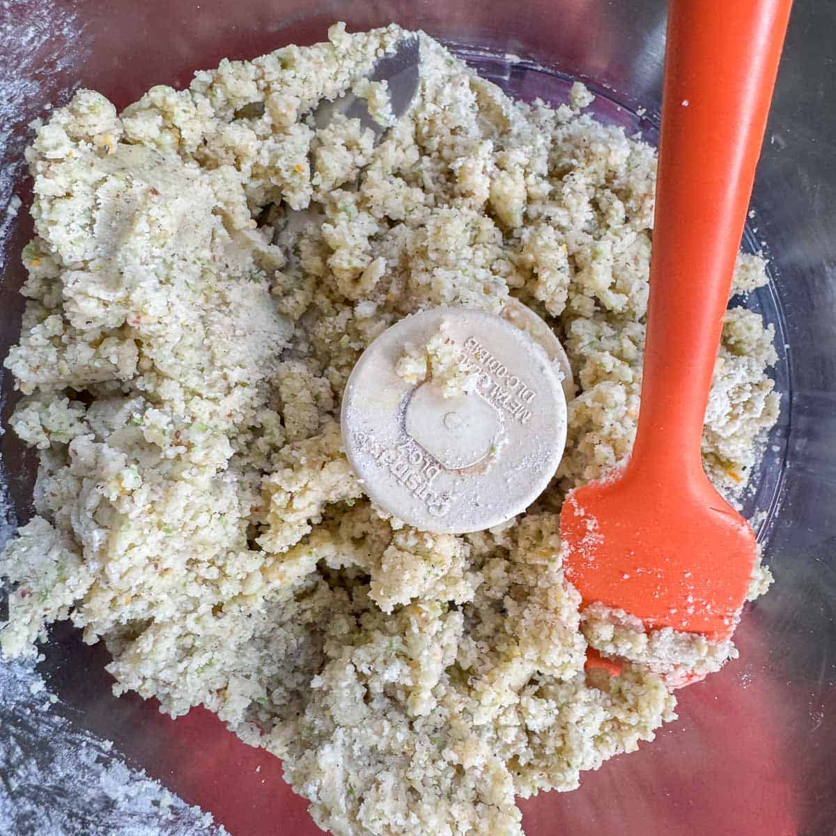 shortbread dough in food processor with an orange rubber spatula