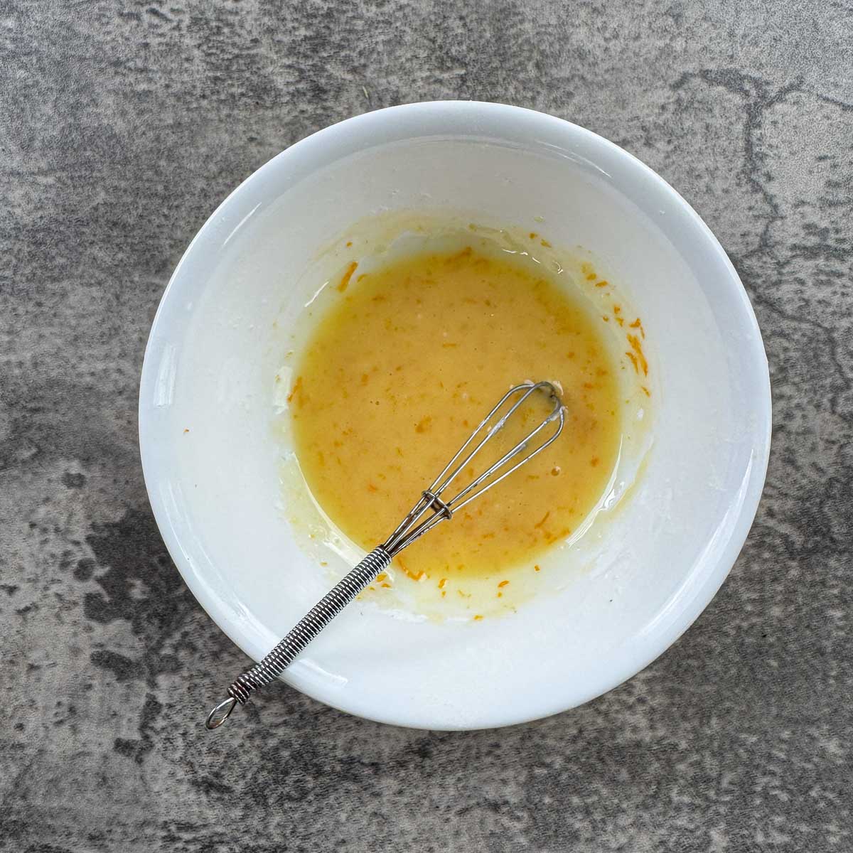 orange glaze in a white bowl with a whisk