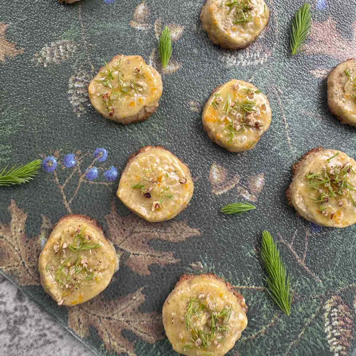 spruce tip shortbread cookies with glaze with more spruce tips around it