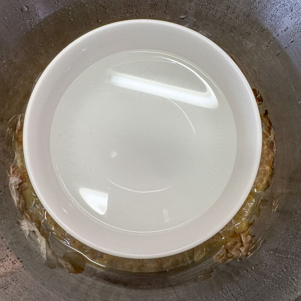 rose water in a white bowl with spent flower petals around it