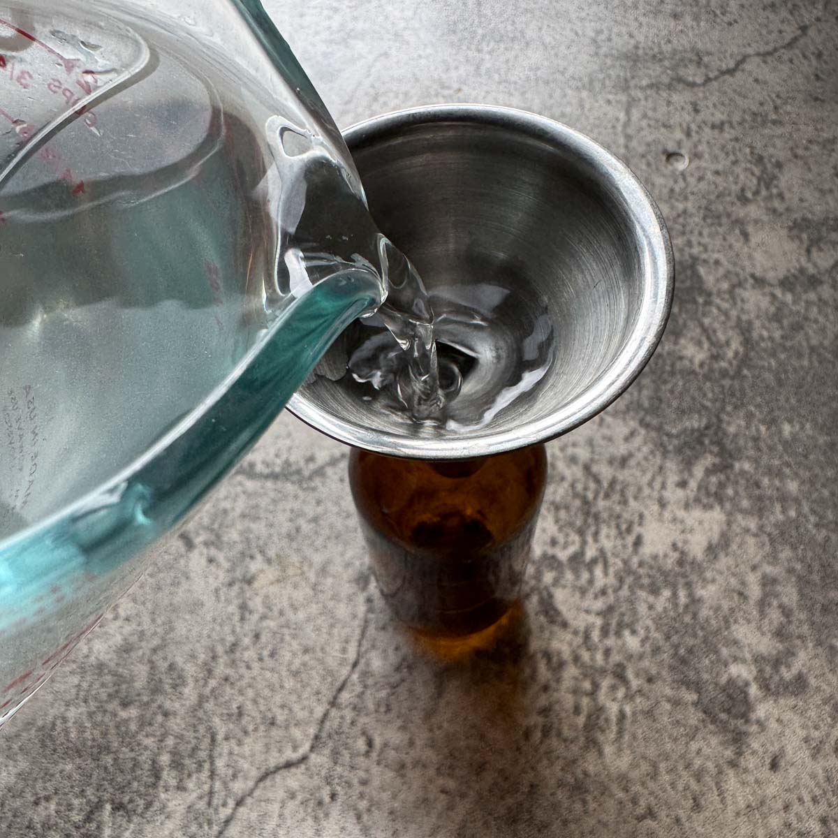 pouring rose hydrosol water into amber bottle