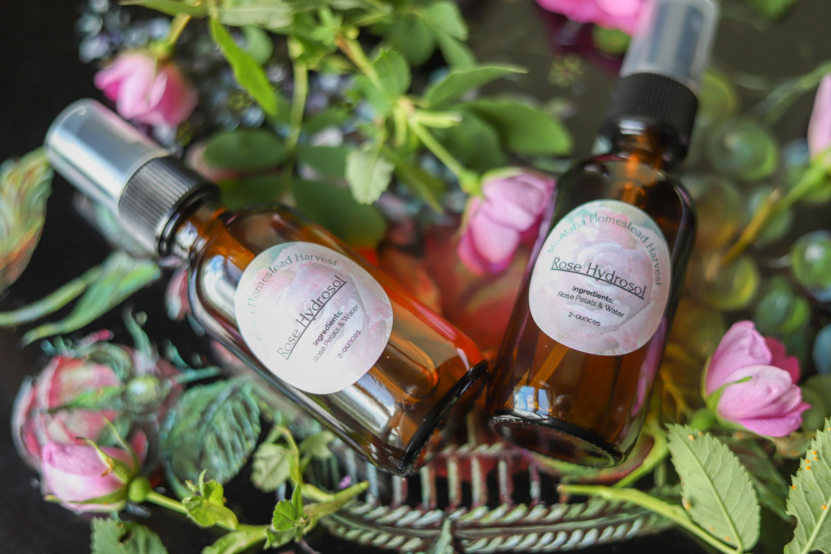 two amber rose hydrosol bottles with roses around them